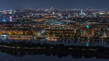Avusturya 'da gökdelenler, tarihi binalar ve nehir kenarındaki gece gezintisi ile Viyana şehrinin hava panoramik manzarası.