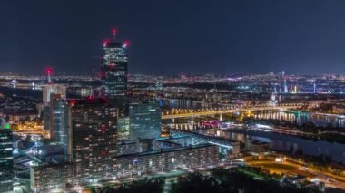 Avusturya 'da gökdelenler, tarihi binalar ve nehir kenarındaki gece gezintisi ile Viyana şehrinin hava panoramik manzarası.