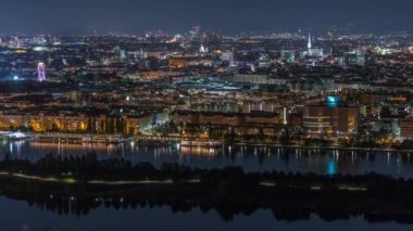 Avusturya 'da gökdelenler, tarihi binalar ve nehir kenarındaki gece gezintisi ile Viyana şehrinin hava panoramik manzarası.