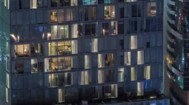 Dış apartman kulesinin gece görüşü. Pencerelerinde yanıp sönen ışıklar olan yüksek gökdelen