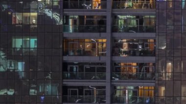 Dış apartman zaman atlamalı gece görünümü. Pencerelerde yanıp sönen ışıklar ile yüksek katlı gökdelen