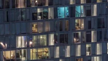 Dış apartman kulesinin gece görüşü. Pencerelerinde yanıp sönen ışıklar olan yüksek gökdelen
