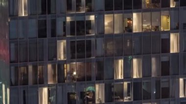 Dış apartman kulesinin gece görüşü. Pencerelerinde yanıp sönen ışıklar olan yüksek gökdelen