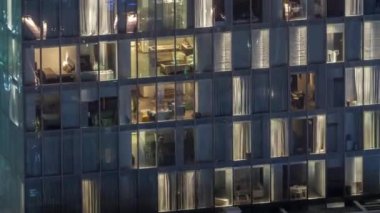 Dış apartman kulesinin gece görüşü. Pencerelerinde yanıp sönen ışıklar olan yüksek gökdelen