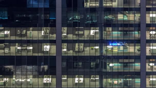Office building exterior during late evening with interior lights on and people working inside night timelapse — Stock Video