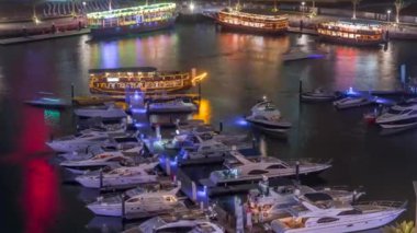 Dubai Marina körfezindeki iskeleye park etmiş lüks yatlar. Şehir hava manzaralı gece manzaralı.