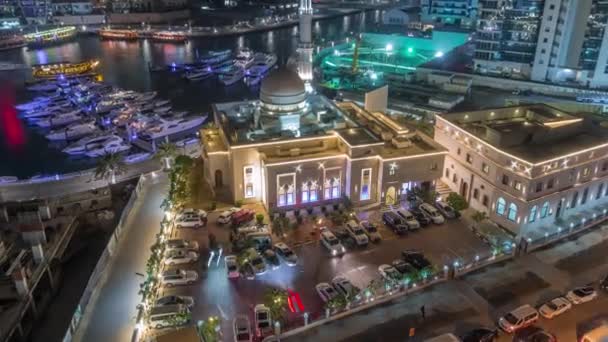 Yachts à Dubai Marina flanqué de la mosquée Al Rahim et tours résidentielles et gratte-ciel timelapse de nuit aérienne . — Video