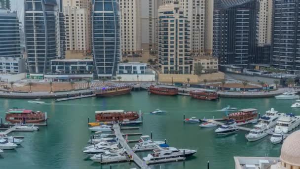 Jachten in Dubai Marina geflankeerd door de Al Rahim moskee en residentiële torens en wolkenkrabbers antenne dag tot nacht timelapse. — Stockvideo