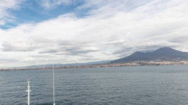Dalgalı deniz manzarası ve açık denizde yelken açan gemiden liman manzarası.