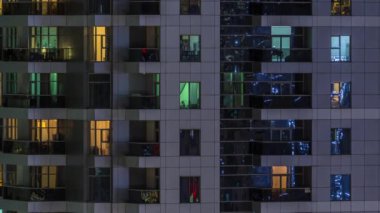 Geceleri apartmanda insanların oturduğu parlak pencereler..