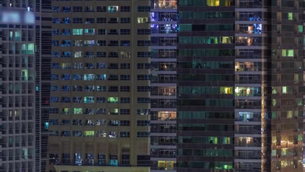 Filas de ventanas brillantes con gente en el edificio de apartamentos por la noche . — Vídeos de Stock