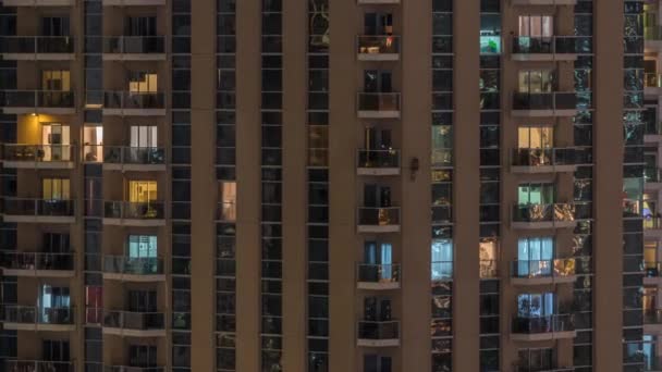 Filas de ventanas brillantes con gente en el edificio de apartamentos por la noche . — Vídeo de stock