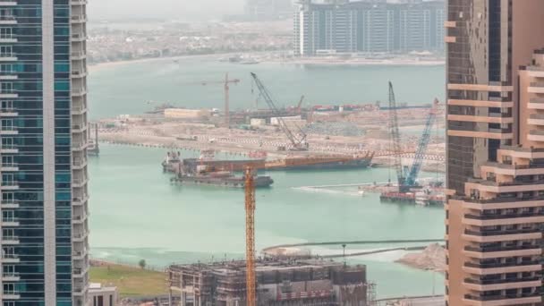 Vista aérea de los rascacielos del puerto deportivo de Dubái con obras de construcción y Palm Jumeirah Island en el timelapse de fondo . — Vídeos de Stock