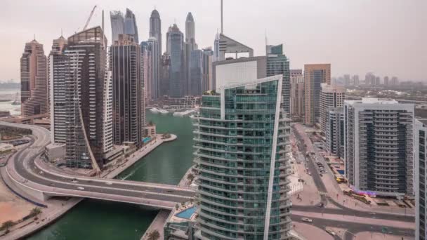 Vista aérea de los rascacielos residenciales y de oficinas de Dubai Marina con timelapse de día a noche frente al mar — Vídeo de stock