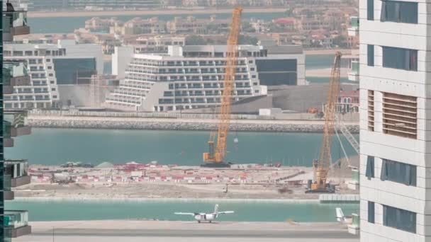 Vista aérea de los rascacielos del puerto deportivo de Dubái con obras de construcción y Palm Jumeirah Island en el timelapse de fondo . — Vídeos de Stock