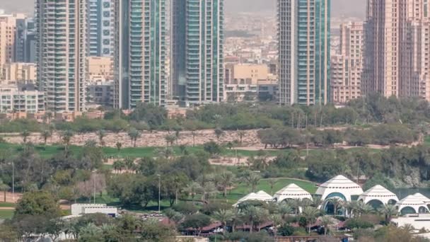 Pole golfowe w Dubaju z pejzażem miejskim dzielnic Gereens i tecom w tle antenowy timelapse — Wideo stockowe