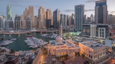 Dubai Marina 'daki yatlar El-Rahim Camii' nin ve konut kulelerinin ve gökdelenlerin yan tarafındaki yatlar gece gündüz gökdelenler.