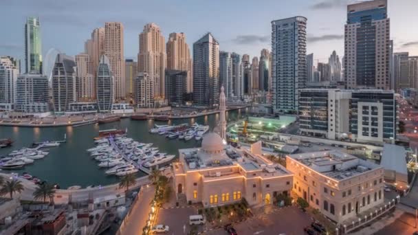 Σκάφη στη Μαρίνα Ντουμπάι πλαισιωμένα από το Τζαμί Αλ Ραχίμ και οικιστικούς πύργους και ουρανοξύστες εναέρια νύχτα με την ημέρα timelapse. — Αρχείο Βίντεο
