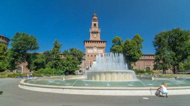Sforza Kalesi 'nin ana girişi - Castello Sforzesco ve önündeki çeşme, Milan, İtalya. Yazın mavi gökyüzü. Etrafta dolaşan insanlar