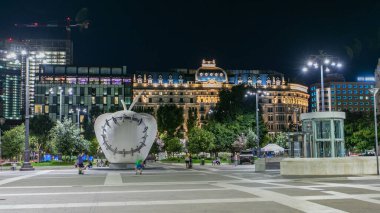 Anıtsal Reintegrated Apple Milan'ın Merkez Tren İstasyonu, Piazza Duca d'Aosta gece timelapse önünde heykel. Aydınlatılmış binalar. Yaz günü, yeşil ağaçlar