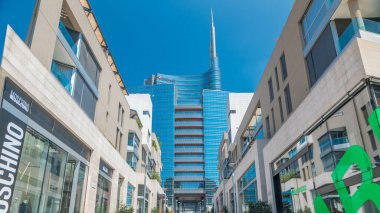 Gökdelen ve Milan finans bölgesine timelapse modern binalarda. Street mağazaları ile. İnsanlar burada yürümeye çalışıyoruz. Mavi bulutlu gökyüzü yaz gün