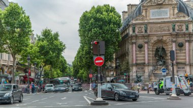 Saint-Michel Meydanı 'nın tarihi çeşmeli sokak manzarası, Paris. Yollarda trafik vardı, arabalar ve insanlar vardı. Yaz gününde bulutlu bir gökyüzü