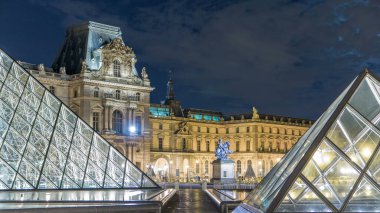 Louvre Piramidinin gece saatlerinde aydınlatıldığı ünlü Louvre Müzesi manzarası. Dolunay. Louvre Müzesi dünyanın en büyük ve en çok ziyaret edilen müzelerinden biridir. Paris, Fransa