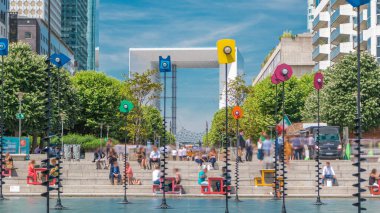 Gökdelenler La Defense timelapse - Modern iş ve konut alanı, Esplanade Çeşmesi. Yeşil ağaçlar, mavi bulutlu gökyüzü güneşli yaz günü. Paris, Fransa