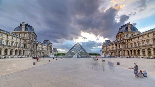 日没時のルーヴル美術館のピラミッドは フランスのパリで経過する 夏の日にカラフルな空 広場を歩く人々 — ストック写真