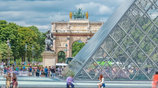 ルーブル ピラミッドと凱旋門は パリで時間が経過した反射のあるカルーセルです ピラミッドはルーヴル美術館の正面玄関として完成した 夏の日に噴水の近くに座っている人 — ストック写真