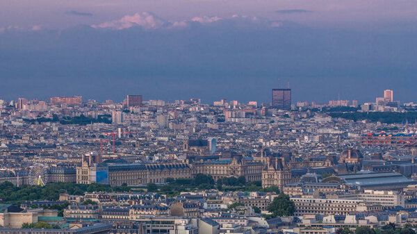Aerial view of a large city skyline with Tuileries park at sunset with orange light timelapse. Top view from the Eiffel tower. Paris, France.