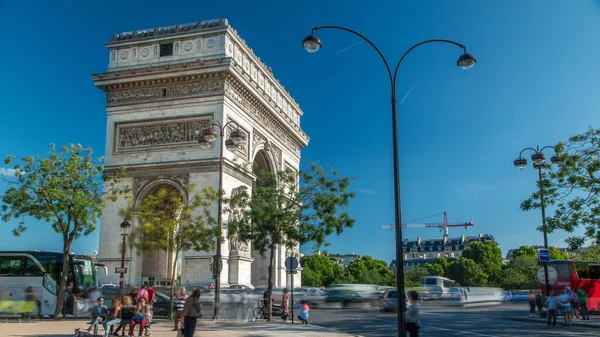 The Arc de Triomphe (Triumphal Arch of the Star) timelapse is one of the most famous monuments in Paris, standing at the western end of the Champs-Elyseees. Traffic on circle road. Blue cloudy sky at summer day
