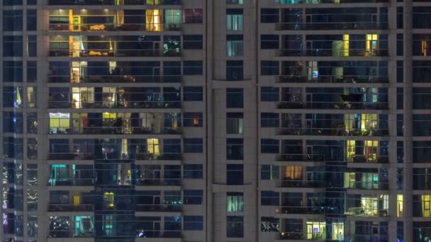 Fénylő ablaksorok emberekkel az apartmanházban éjszaka.. — Stock videók