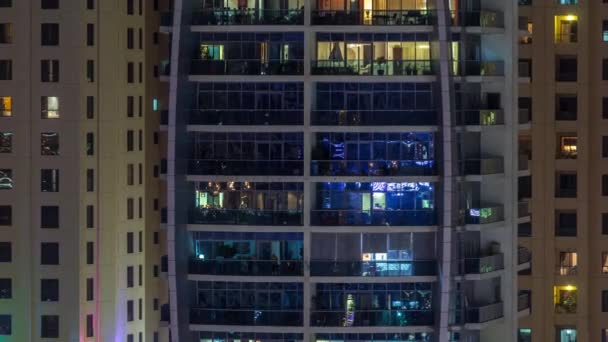 Filas de ventanas brillantes con gente en el edificio de apartamentos por la noche . — Vídeos de Stock