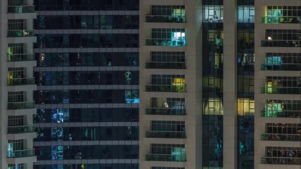 Filas de ventanas brillantes con gente en el edificio de apartamentos por la noche . — Vídeos de Stock