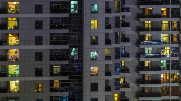 Rækker af glødende vinduer med folk i lejligheden bygning om natten . – Stock-video