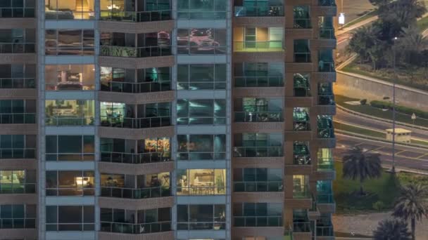 Des rangées de fenêtres rougeoyantes avec des personnes dans l'immeuble la nuit . — Video