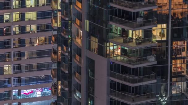 Rader av glödande fönster med människor i lägenhetsbyggnad på natten. — Stockvideo