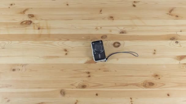 Digital cameras moves on small tripod on wooden table timelapse stop motion — Stock Video