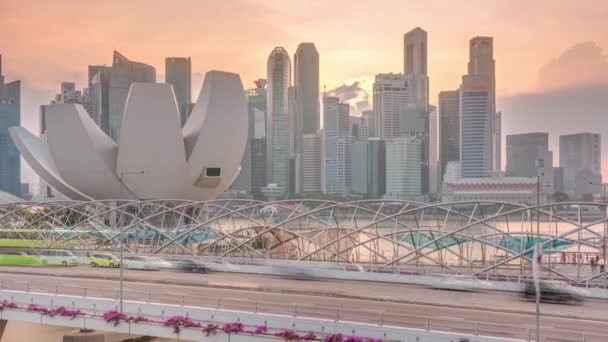 मरीना बे, सिंगापूर येथे वाहतूक टाइमलॅप्ससह हेलिक्स ब्रिज आणि बेफ्रंट अव्हेन्यू प्रती सूर्यास्त हवाई दृश्य — स्टॉक व्हिडिओ