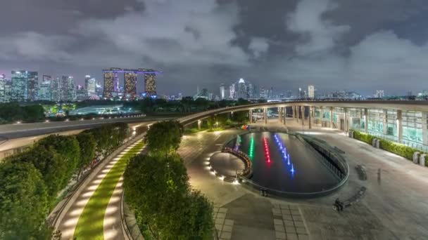 Vista aérea de Singapur horizonte de la ciudad con colorida fuente en Marina bombardeo jardín noche timelapse. — Vídeo de stock
