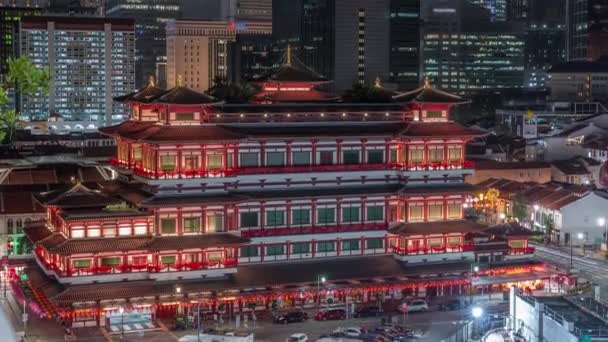 El templo de la reliquia de Buda cobra vida por la noche en el barrio chino de Singapur, con el horizonte de la ciudad al fondo . — Vídeo de stock