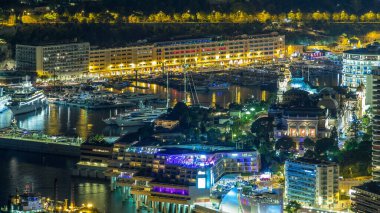 Monako 'nun hava manzarası. Büyük Corniche Yolu' ndan. Gece Zaman Alanı, Monako Fransa. Akşam aydınlatması. Yollarda trafik vardı. Limandaki yatlarla yansıyan yansımalar.