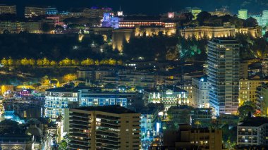 Monako 'nun Monako' daki Princely Palace, Monako 'daki büyük Corniche Yolu' ndaki gece manzarası. Akşam aydınlatması. Yolda trafik vardı..