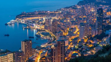 Monako 'nun büyük Corniche yolundan gece geçiş zamanına, Monako Fransa' ya giden hava manzarası. Akşam aydınlatması. Limanın suyundaki yansımalar