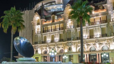 Monaco, Monte Carlo 'da gece vakti el fıskiyeleri ve çeşmeleri olan bir kumarhane meydanı. Arkaplanda yeşil çimenler ve tarihi yapılar