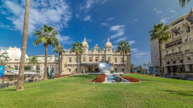 Monte Carlo, Monaco 'daki Grand Casino' nun ön görüntüsü. Çeşmeli ve yeşil çimenli tarihi bina ve meydan. Avuçlar yana. Yazın mavi bulutlu gökyüzü