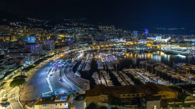 Monte Carlo 'nun Panorama' sı geceleyin Herkül Limanı ile Monako köyündeki gözlem güvertesinden. Liman manzaralı, aydınlık binalar ve yatlar. Yolda trafik vardı.