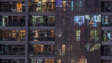 Dış apartman zaman atlamalı gece görünümü. Pencerelerde yanıp sönen ışıklar ile yüksek katlı gökdelen