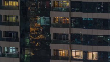 Dış apartman zaman atlamalı gece görünümü. Pencerelerde yanıp sönen ışıklar ile yüksek katlı gökdelen
